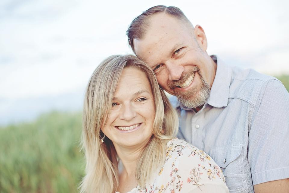 Alicia and her husband smiling in a grassy field